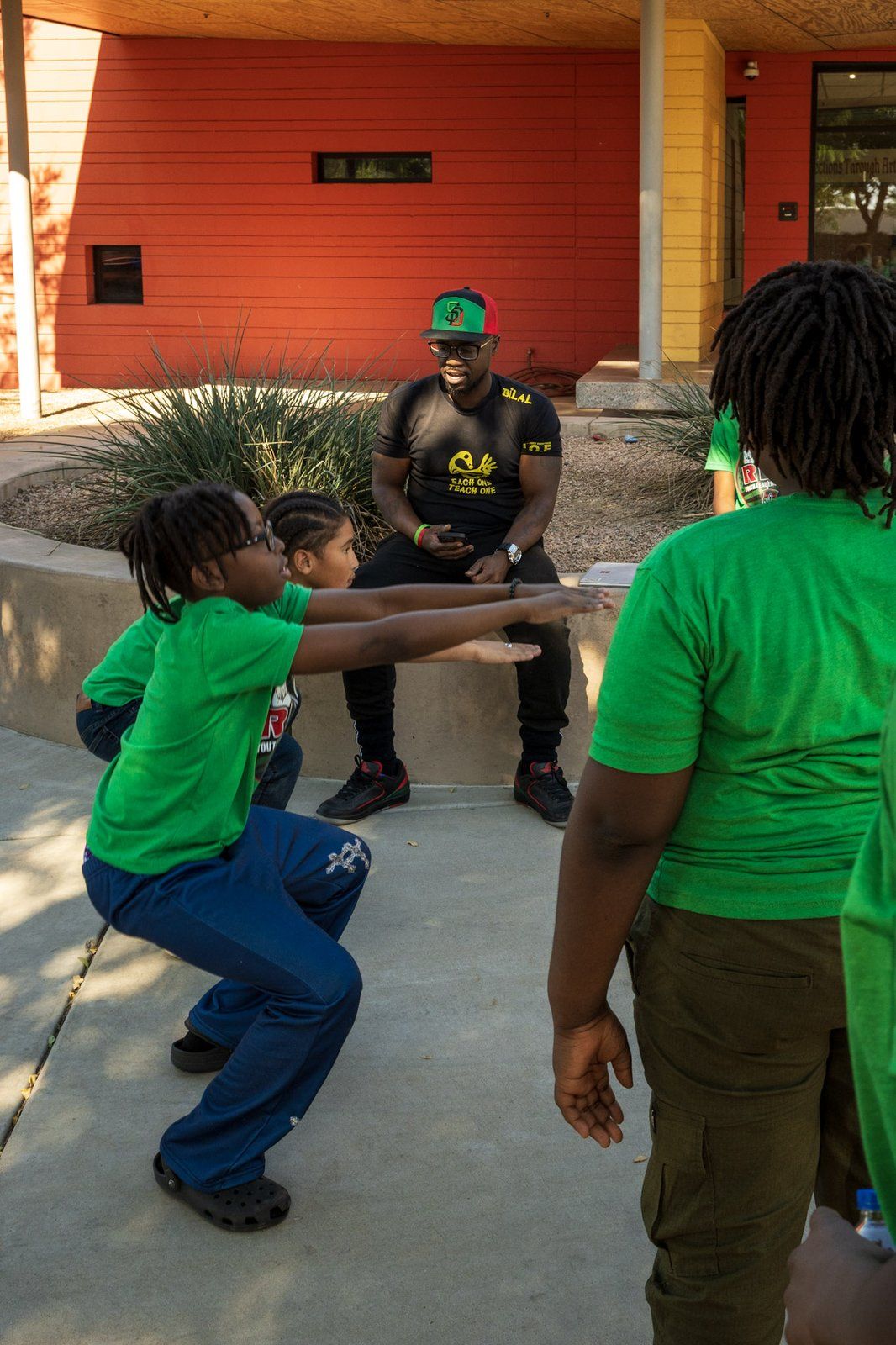 A mentor guiding two young mentees through a movement exercise