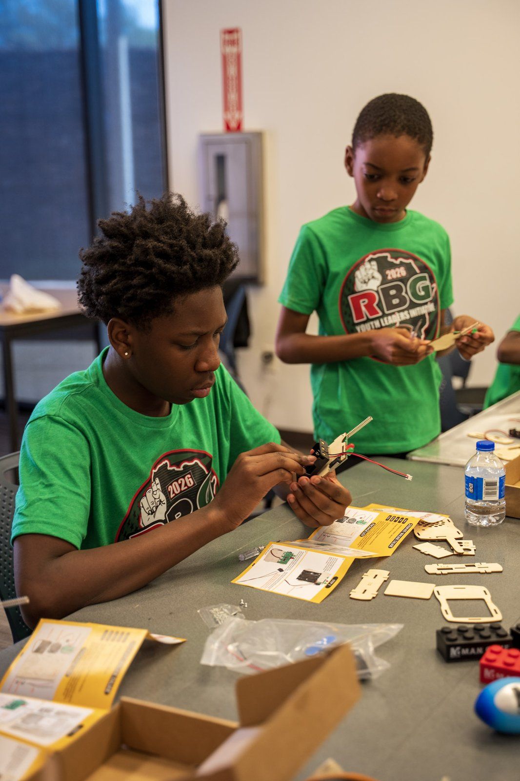 A mentee in an RBG Youth Leaders Initiative shirt assembling a kit at a workshop table