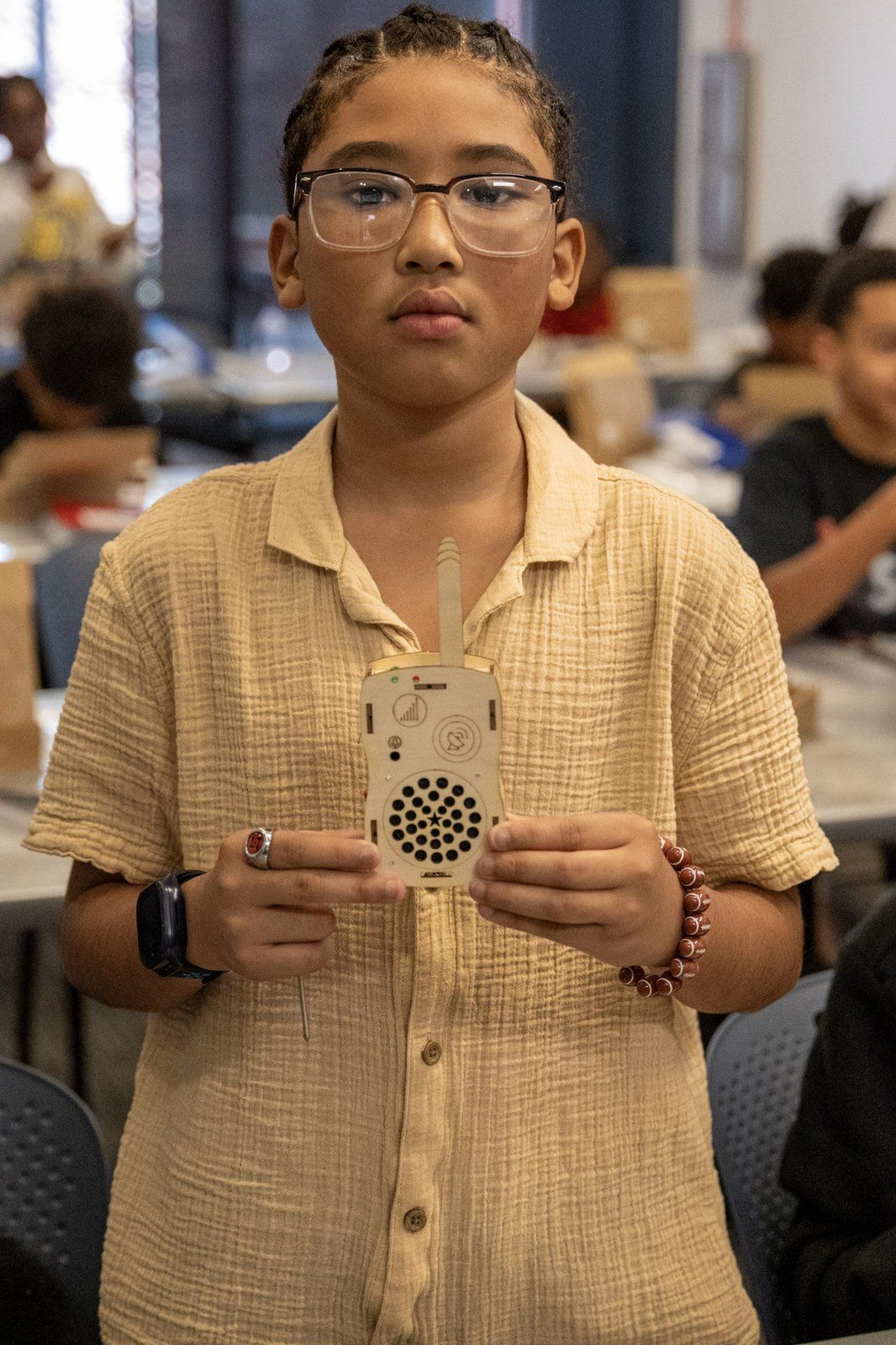 A young mentee holding up a finished electronics project