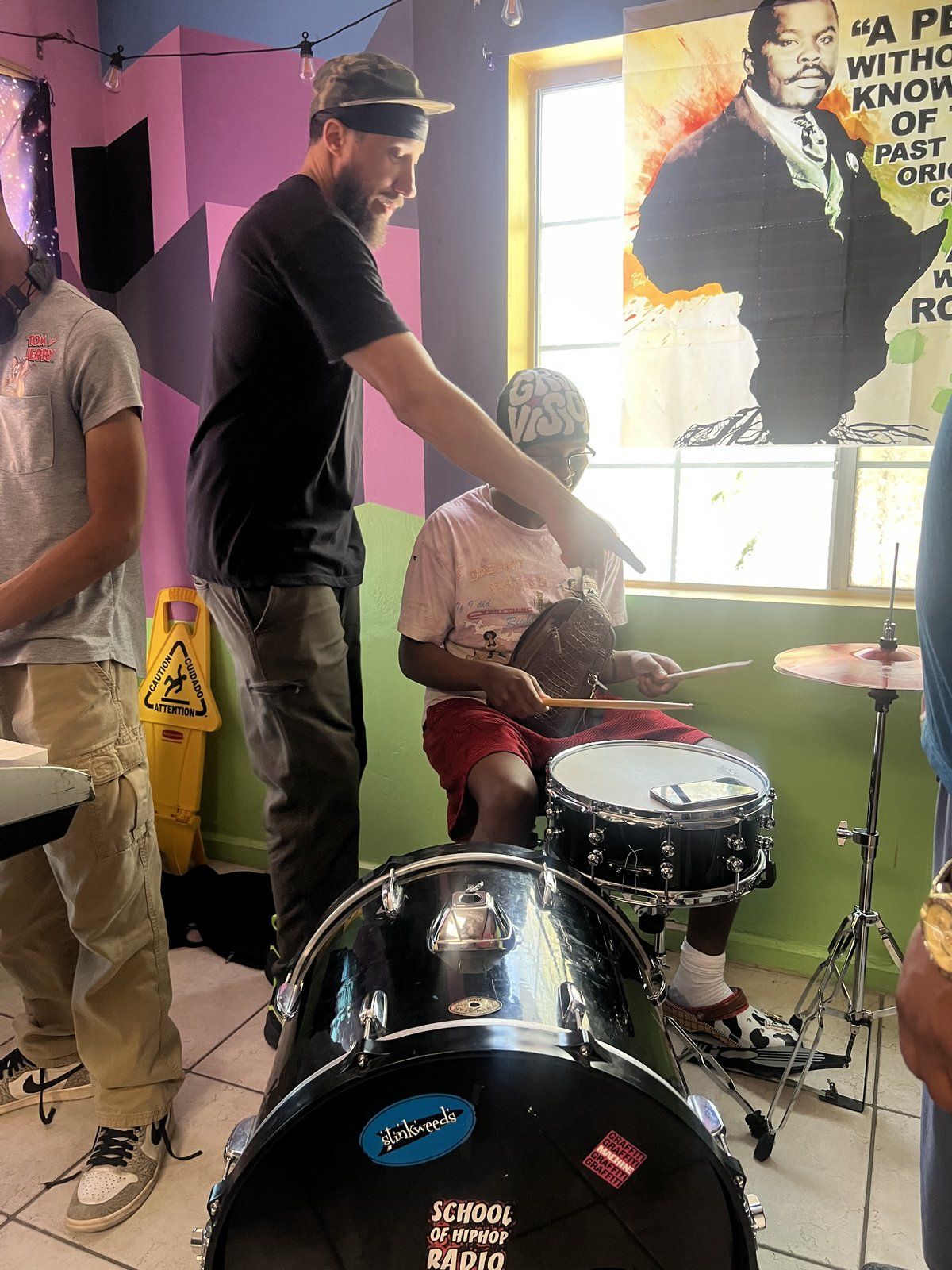 A music mentor coaching a mentee on drums