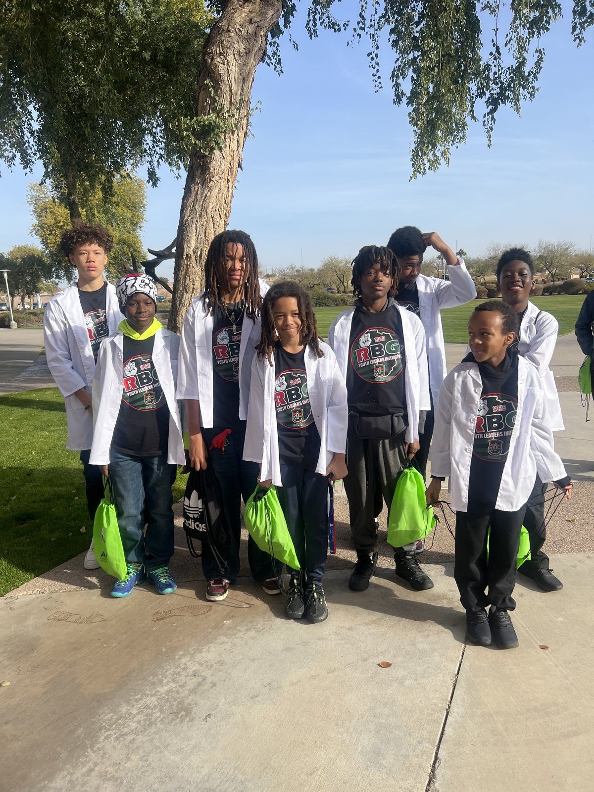 Mentees in white lab coats posed outdoors at a youth summit