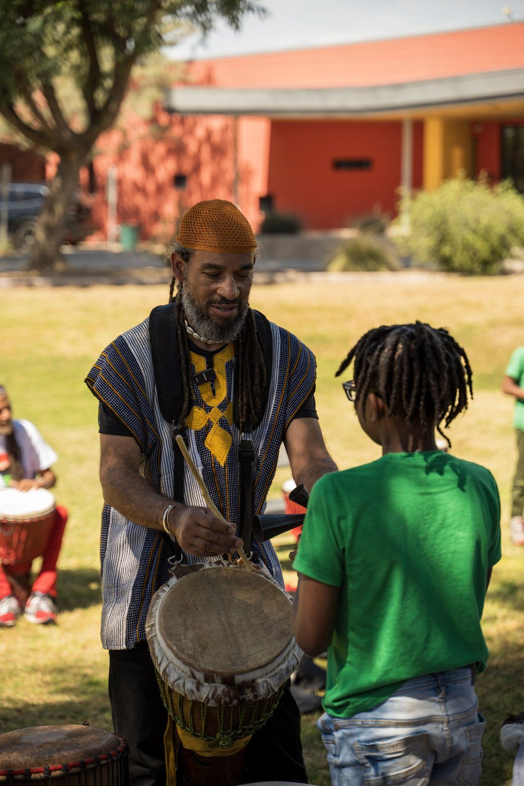 A drummer teaching a young mentee outdoors