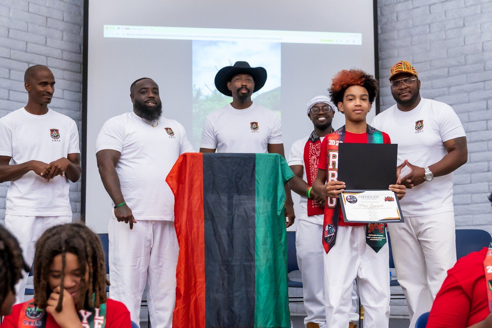 A young mentee receiving a certificate on stage