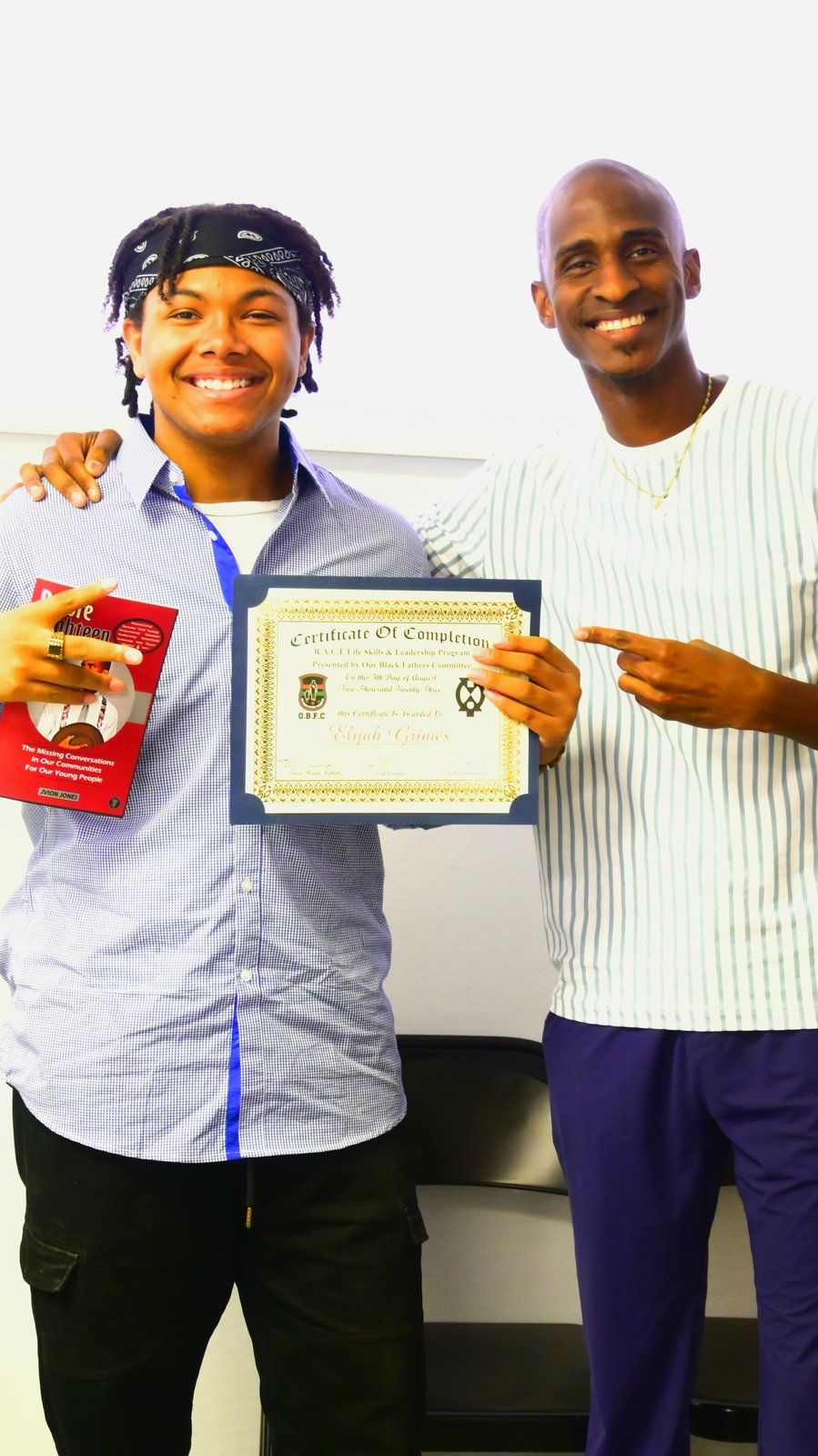 A mentor congratulating a mentee holding a certificate