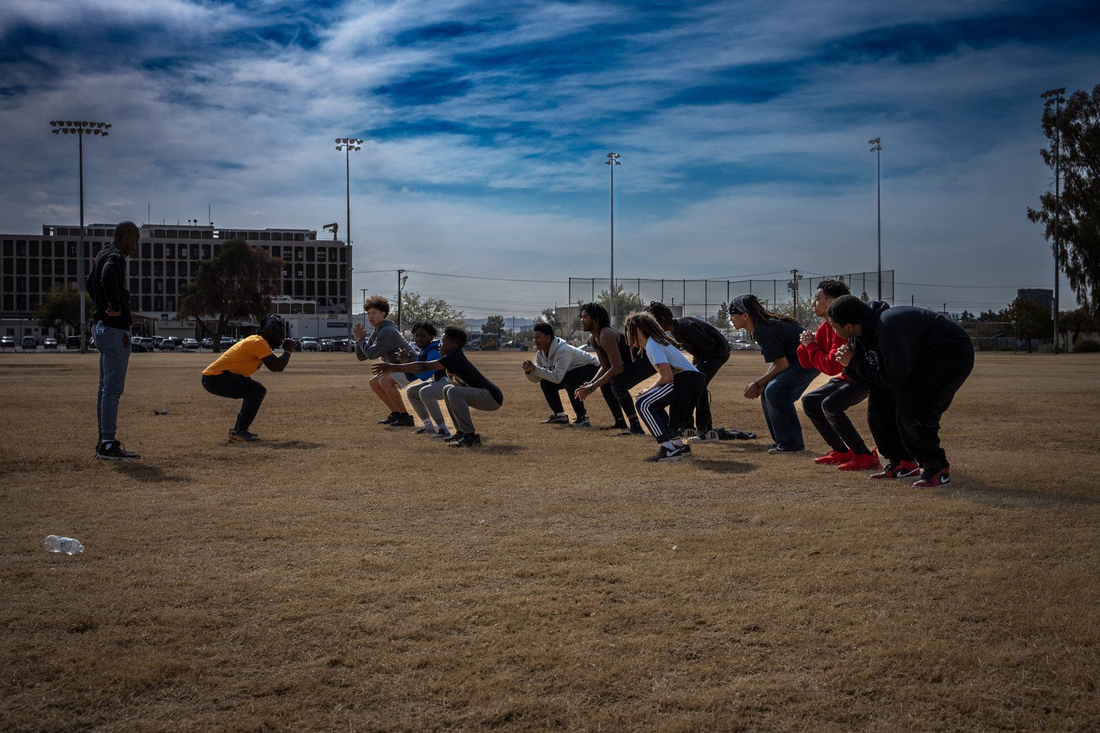 Mentees and mentors doing a fitness exercise on a field at dusk