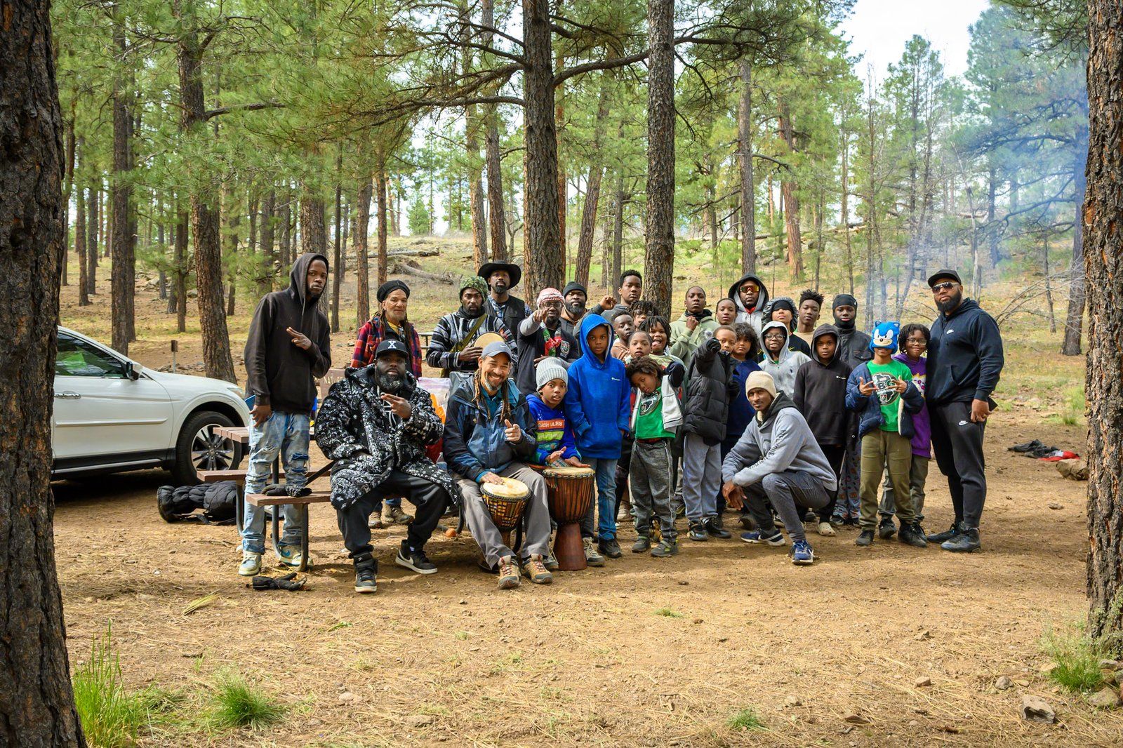 A group gathered among pine trees during a camping trip