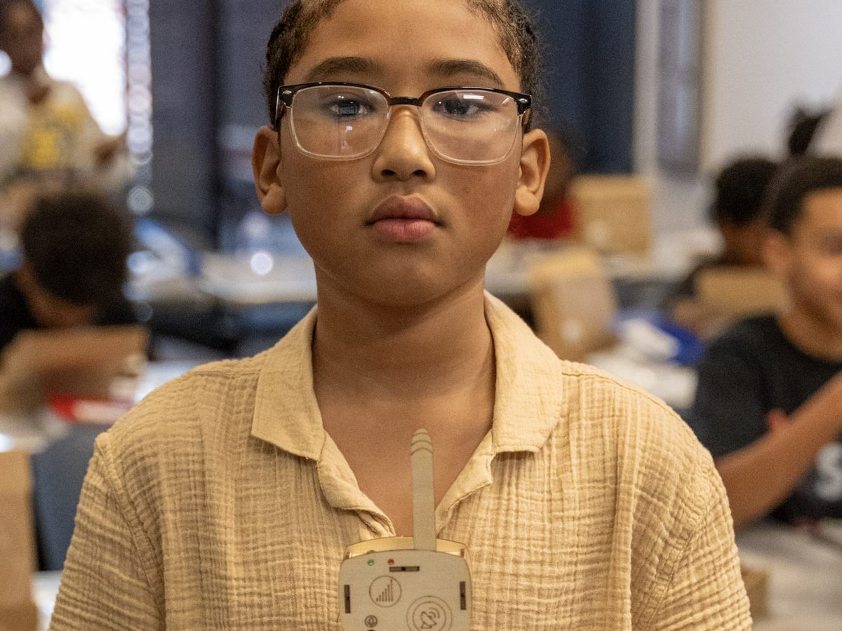 A young participant holds a small device he built during a STEAAM session.